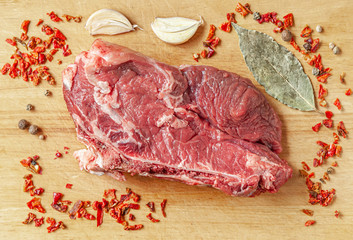 Wall Mural - raw beef with a bone decorated with spices and garlic on a wooden cutting board flat lay