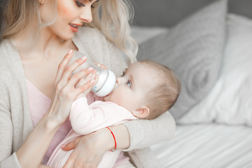 Wall Mural - Mother feeding her little baby. Child eating formula.