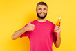 © LIGHTFIELD STUDIOS - happy bearded guy in pink t-shirt showing thumb up with beer on yellow