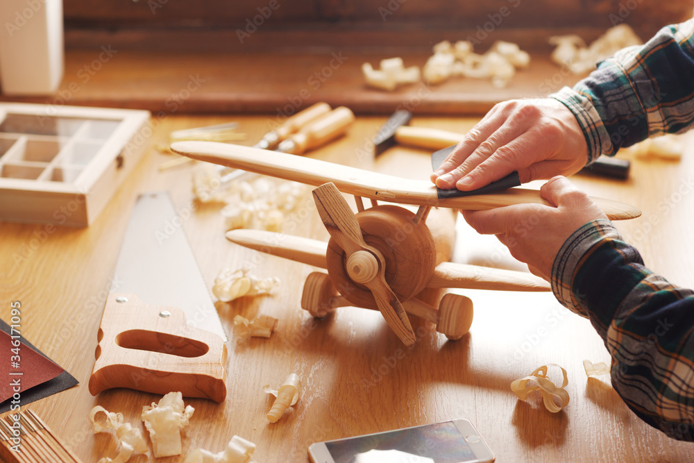 Craftsman building a wooden toy airplane - obrazy, fototapety, plakaty 