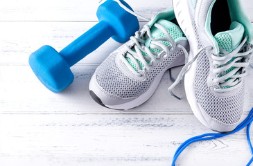 1 blue dumbbell, skipping rope, gray sneakers on a gray  top view