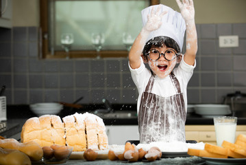 happy cute asian little boy in apron preparing baking the dough in kitchen room at home