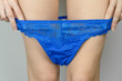 Close-up of slender legs of a young woman who takes off beautiful blue panties
