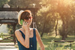 © astrosystem - Young woman using smartphone in the park.