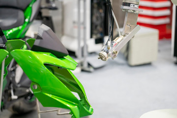 Wall Mural - The painting robot spray the green color to the motorcycle mask parts. The automatic automotive parts painting system by robotics system.