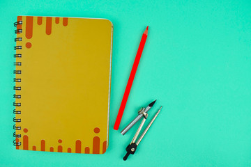 Sticker - Compass placed besides pencil and a orange color note paper diary on a light blue background