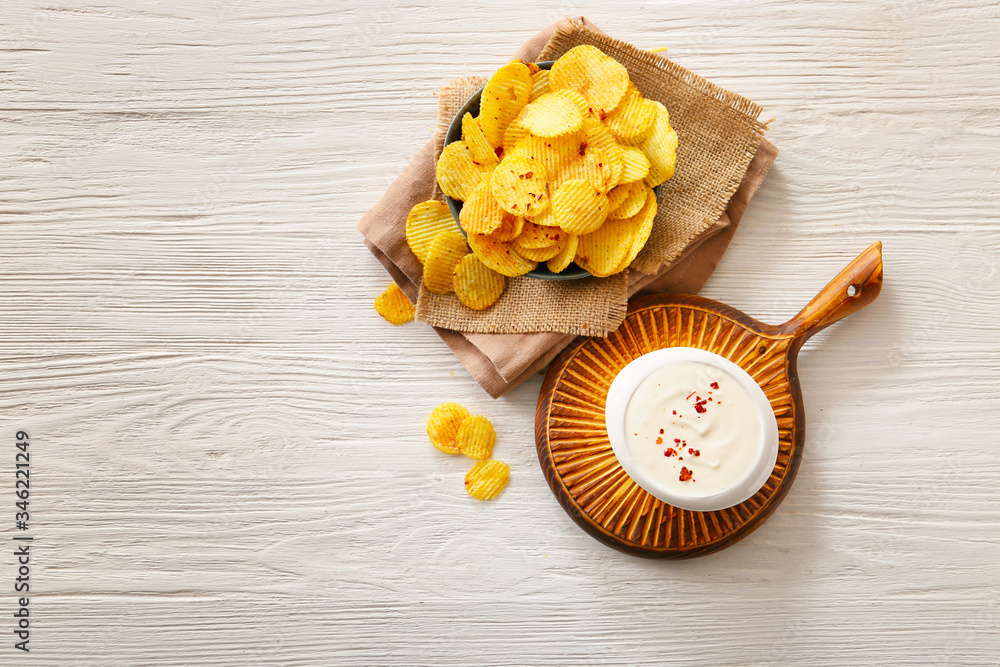 Bowl with tasty sour cream and potato chips on table