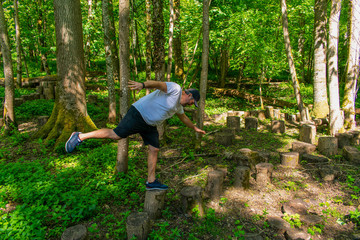 A man balancing on a tree trunk beam in a forest.  Having fun outdoors in the English countryside.