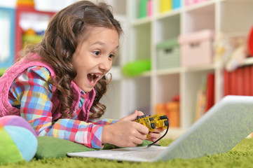 Cute girl playing computer game with laptop