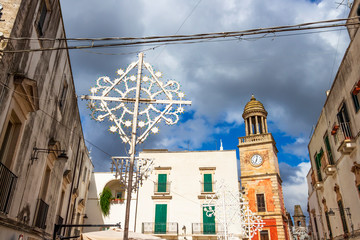 Noci, Italy beautiful high section streetscape with street decoration for La Festa di San Rocco or Saint Roch's Feast and the Clock Tower in the background in Apulia Region, Metropolitan City of Bari