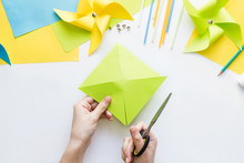 How To Make Paper Green Windmill Toy With Children At Home. Step By Step Instructions. Hands Making DIY Summer Project. Step 5. Cut Sheet In Lines To Circle In Center, Getting Half-cut Triangles.