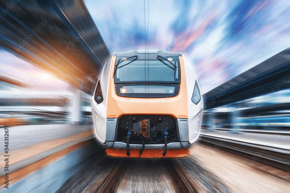 High speed train in motion on the railway station at sunset. Fast ...