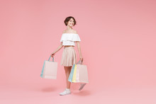 Smiling Young Woman Girl In Summer Clothes Hold Package Bag With Purchases Isolated On Pastel Pink Wall Background Studio Portrait. Shopping Discount Sale Concept. Mock Up Copy Space. Looking Aside.