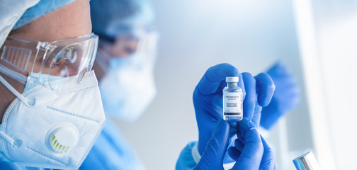 Wall Mural - coronavirus covid-19 vaccine bottle in hands of pharmacuetical and vaccine research scientist in lab