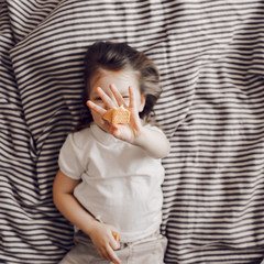 Portrait of beautiful cute little 3 years girl lying on bed in dress and looking at the camera