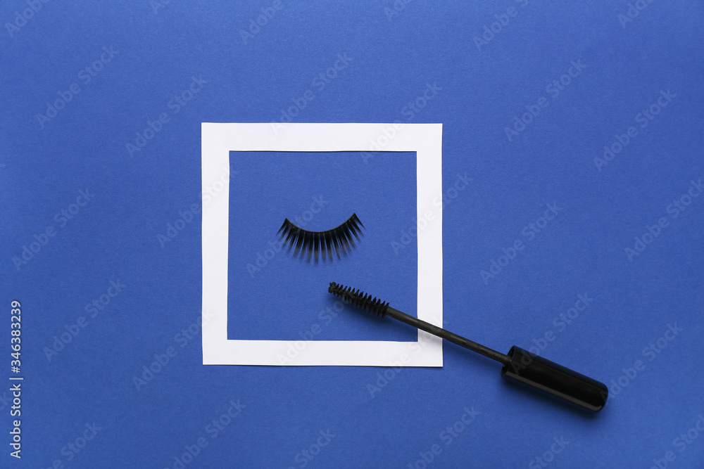 Mascara and fake eyelashes on color background