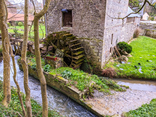 18th century old watermill with wooden wheel along a stream or small river