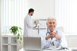 © New Africa - Portrait of senior doctor in white coat at workplace