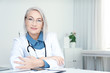 © New Africa - Portrait of mature female doctor in white coat at workplace