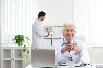 Canvas Print - Portrait of senior doctor in white coat at workplace