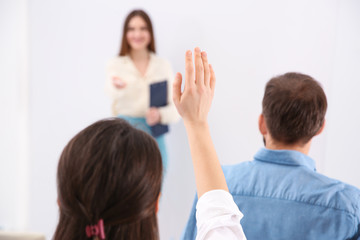 Wall Mural - Young woman raising hand to ask question at business training indoors, closeup