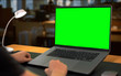 © Artur - Man sitting by table with laptop Green Screen mock up