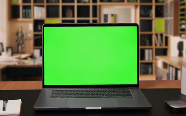 laptop computer with green screen mock-up on working desk in office with no people