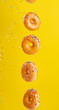 © Anton - Various decorated donuts in motion falling on a yellow background. Sweet and iced donuts fall or fly in motion. With caramel. Yellow background, vertical photo.