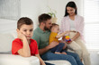 © New Africa - Unhappy little boy feeling jealous while parents spending time with his baby brother at home