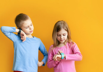Happy children 6-8 years old with a smart GPS watch talking to parents safely. orange background