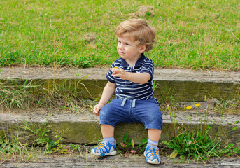 Little boy sits on the steps outdoors.