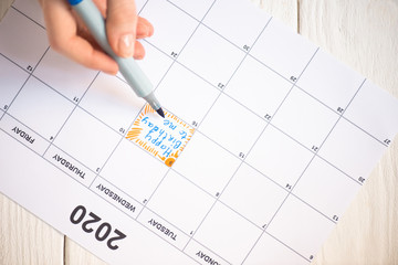 Cropped view of woman pointing with marker pen on happy birthday to me lettering in to-do calendar with 2020 inscription on wooden background