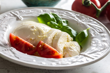 Wall Mural - Mozzarella cheese tomatoes basil and olive oil. Caprese salad - italian or mediterranean meal or appetizer