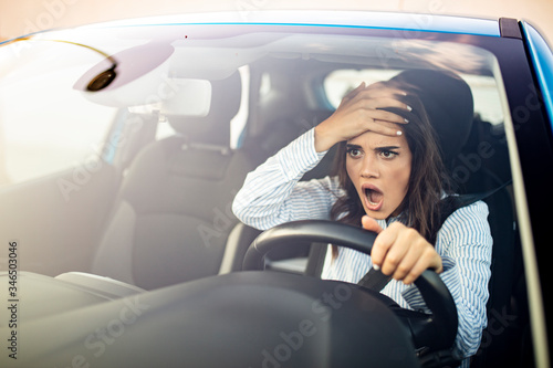 Furious woman stucked in traffic jam. A furiously angry woman driving grimaces, shaking her fist through the windscreen in a bout of road rage! Road rage traffic jam concep