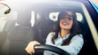 © Dragana Gordic - Happy brunette woman driving a car. Portrait of beautiful caucasian woman with toothy smile and brown hair driving car. Hand on steering wheel. Young woman driving a car in the city
