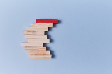 Stack of wooden blocks with red plank on top. Not like everyone. Uniqueness and originality. Stand out from the crowd