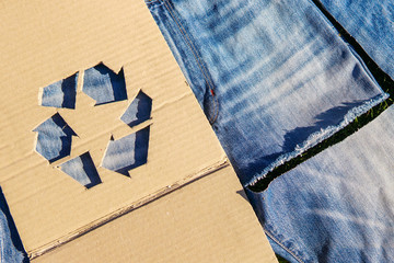 Wall Mural - Recycle symbol on denim fabric over green grass. New skirt from old boyfriend jeans