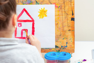 Poster - Child is drawing house with watercolors on the easel.