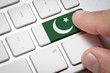 Online International Business concept: Computer key with the Pakistan on it. Male hand pressing computer key with Pakistan flag.
