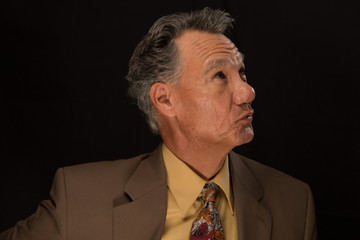 Wall Mural - Portrait of a Mature Business Man Wearing a Tie and Jacket against a Black Background