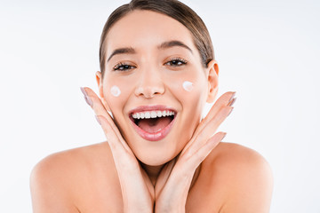 Canvas Print - Happy caucasian young woman applying cream on her skin isolated on white background