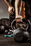 Dłonie trzymające kettlebell, sportowiec uprawiający crossfit, podnoszenie ciężarów.