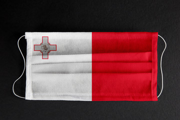 Wall Mural - Coronavirus covid pandemic in Malta. Flag of Malta printed on medical mask on black background. National healthcare system concept. Covid-19 outbreak, quarantine in Valletta, Malta.