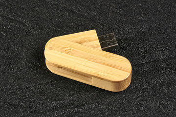 usb flash drive made of bamboo on black concrete. copy space. side view. close up