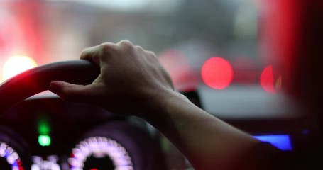 Wall Mural - Person hand holding car steering wheel waiting in traffic jam. Driver POV