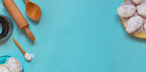 Design concept of making traditional cyprus cookies, baking wooden spoons, rolling pin, metal molds, sugar powder,layout top view, flat lay, overhead, blank copy space on blue background