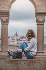 Wall Mural - Young woman in the fishermen's bastion in Budapest, in the background the budapest parliament