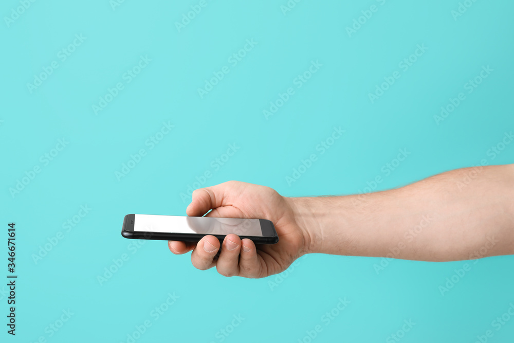 Male hand with mobile phone on color background