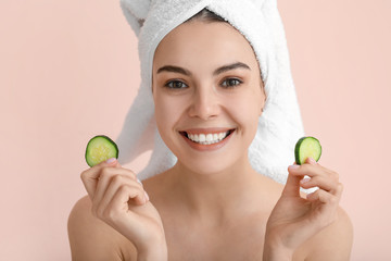 Poster - Beautiful young woman with cucumber slices on color background