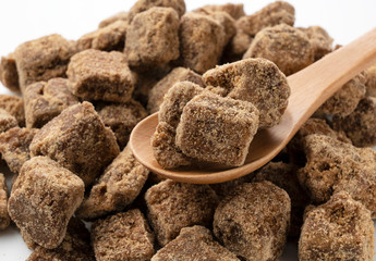 Close-up shot of a lump of brown sugar in a wooden spoon